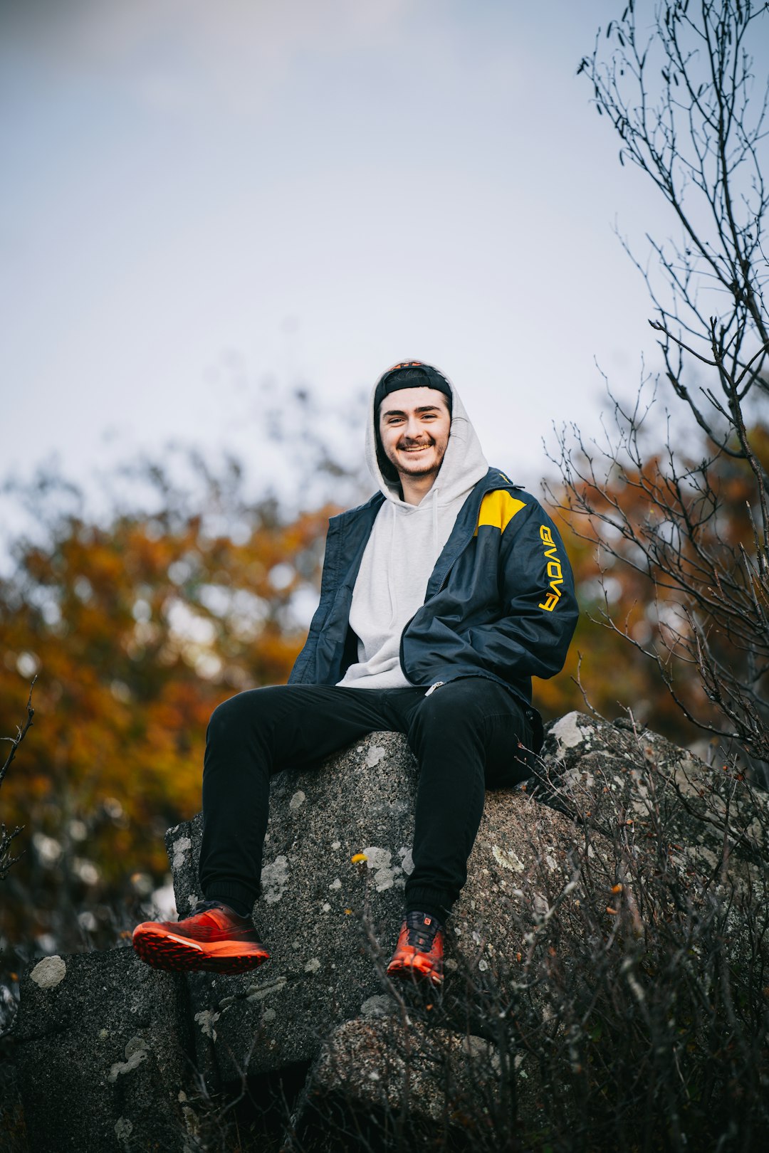 How to Choose the Perfect Men’s Sweatshirt – A Complete Guide by JASON NEXOR LLC Guy with a white hoodie smiling sitting on a rock