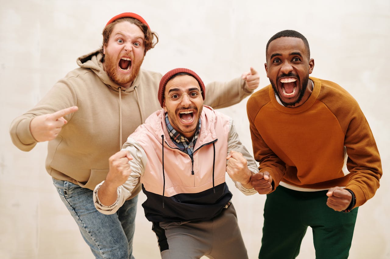 social-feed-img-05 Three diverse men joyfully celebrating together indoors, showcasing friendship and excitement.